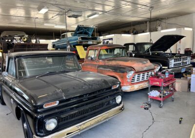 Row of 3 classic chevy trucks in a shop.